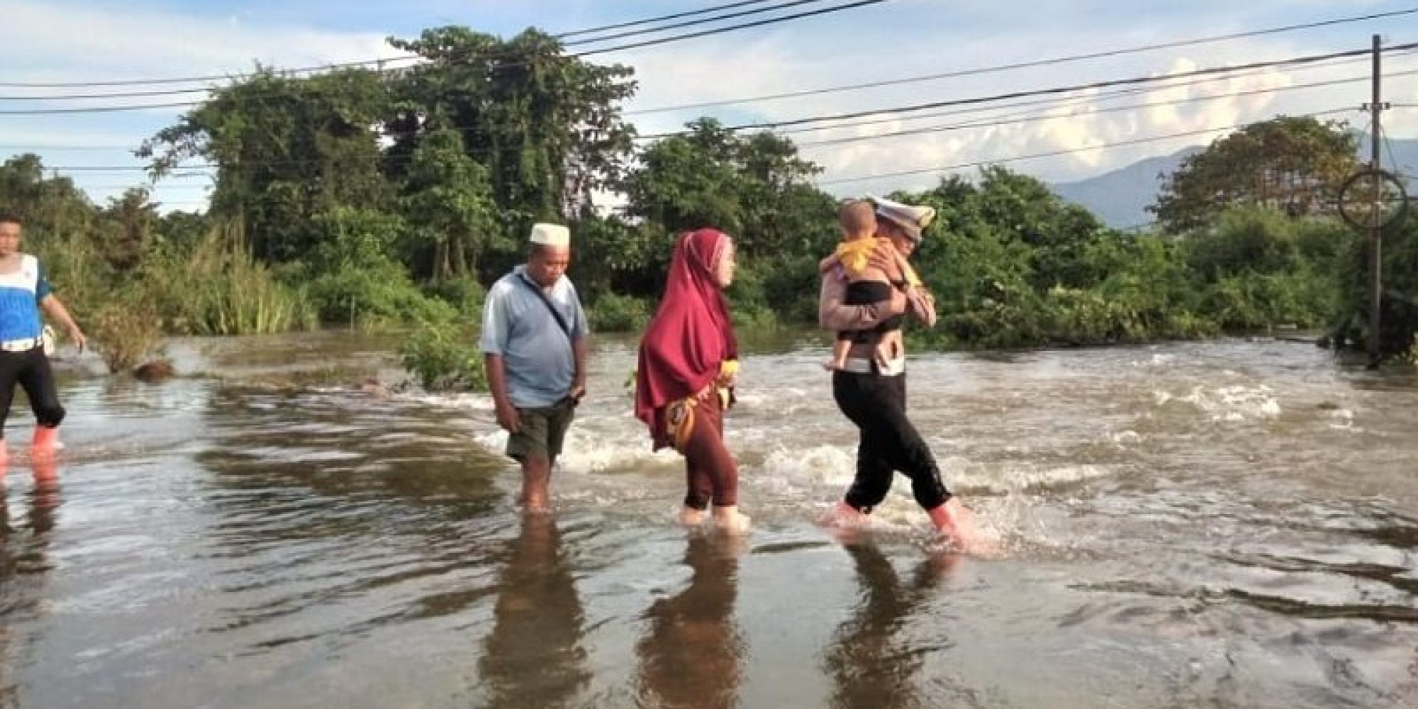 Air Sungai Meluap Hingga Ke Jalan, Personil Polres Konut Membantu Warga Mengevakuasi Warga Yang Tergenang Banjir