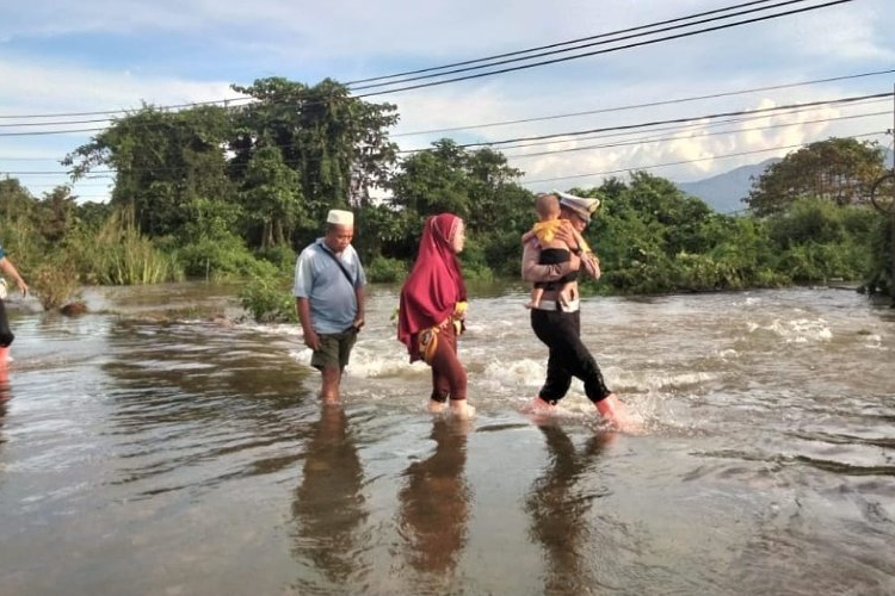 Air Sungai Meluap Hingga Ke Jalan, Personil Polres Konut Membantu Warga Mengevakuasi Warga Yang Tergenang Banjir